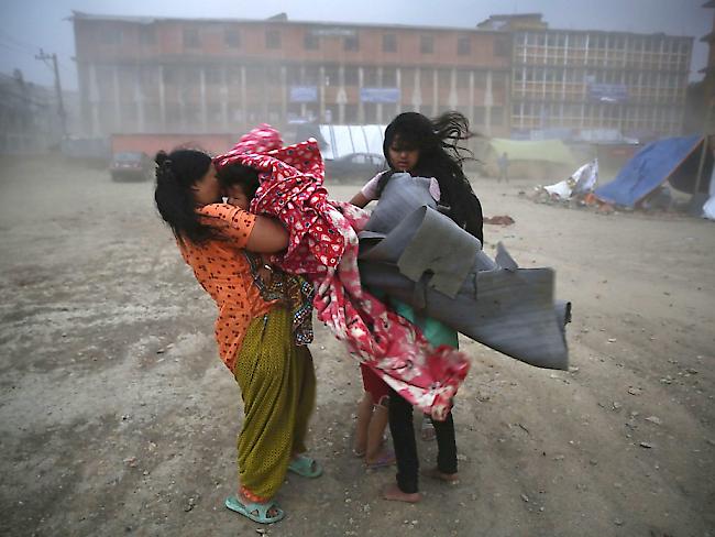 Schwierige Wetterbedingungen machen den Erdbebenopfer Nepals das Leben zusätzlich schwer. In Kathmandu bringen sich Bewohner einer Notunterkunft vor einem Sturm in Sicherheit. Andernorts lösten schwere Regenfälle Erdrutsche aus. Dorfbewohner flohen aus Angst vor einer Flutwelle. (Archiv)